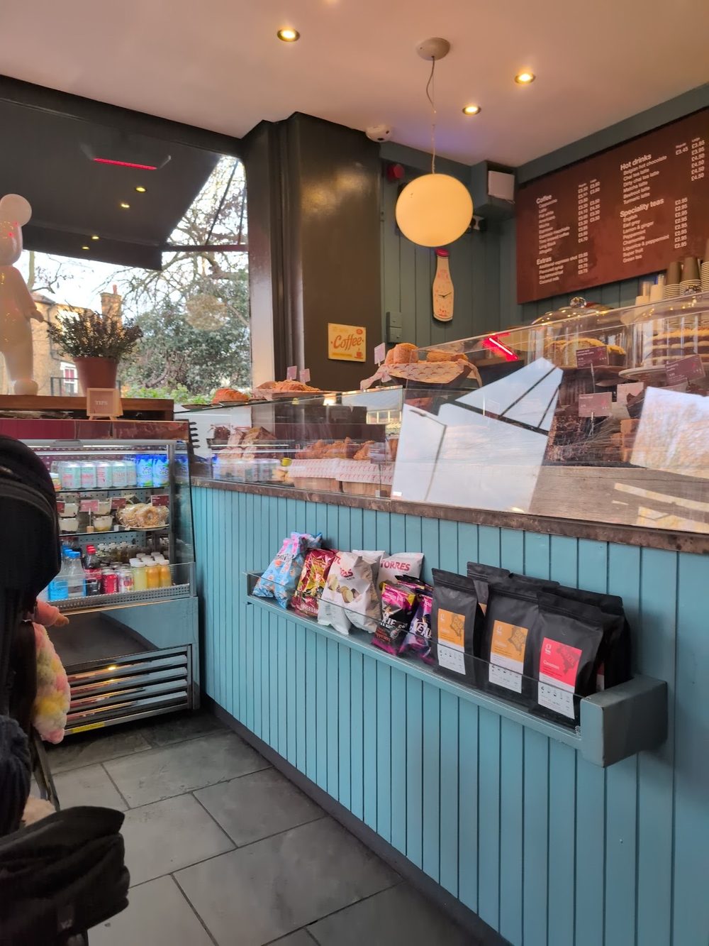 The teal panelled service counter with retail coffee bags and menu boards above