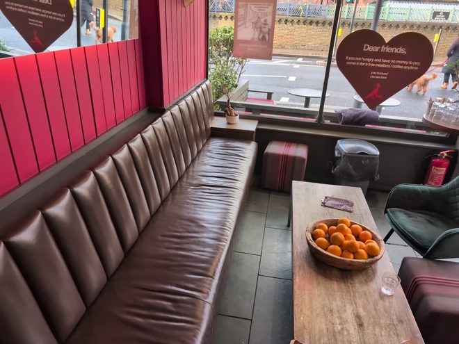 The leather banquette along the red wall with a bowl of oranges